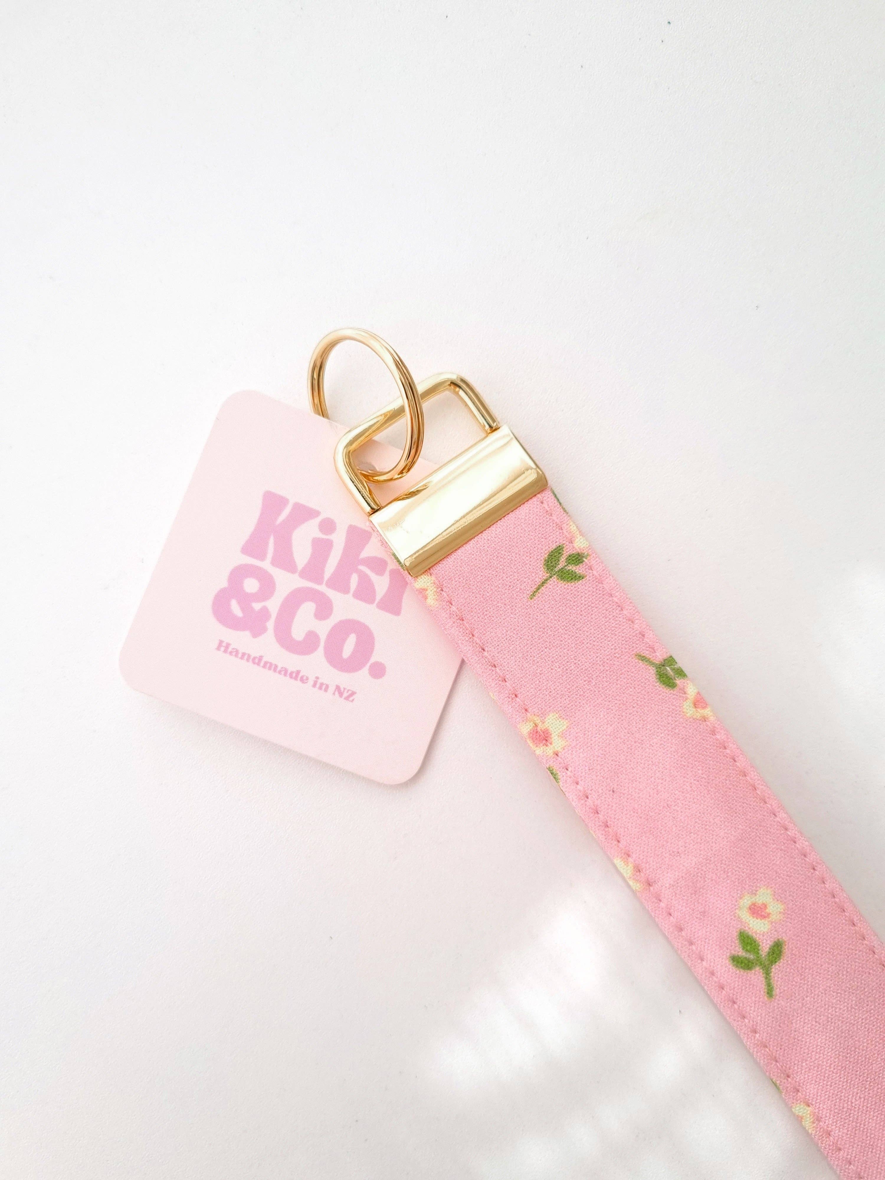 Pink petal keychain by Kiki & Co. with a delicate floral design, attached to a silver keyring.
