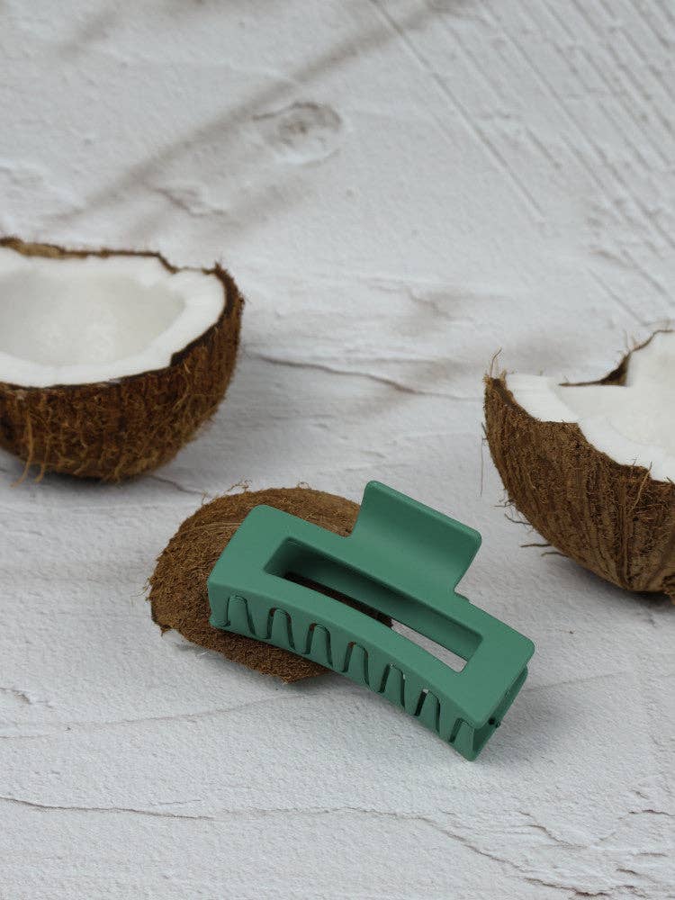 Nakoa The Label pine green elongated rectangle claw clip holding hair, made of durable plastic with a sleek design.