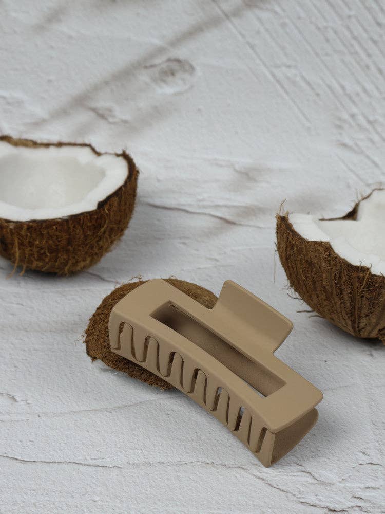 Medium beige elongated rectangle claw clip by Nakoa The Label, shown holding hair in a natural style.