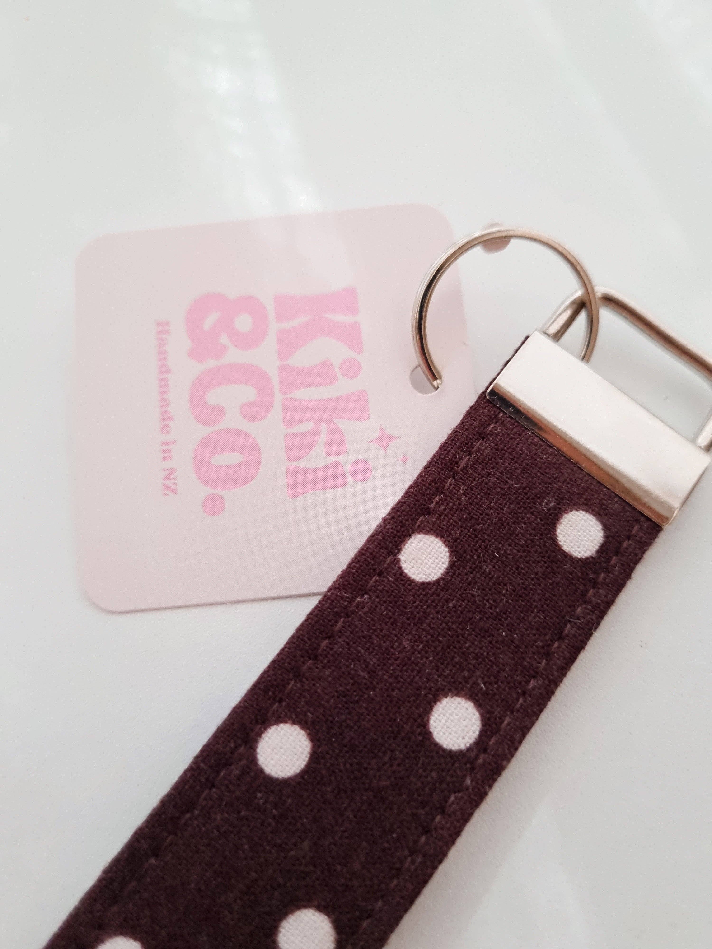 Kiki & Co. chocolate polka dot keychain with a fabric loop and metal keyring, featuring a playful polka dot pattern.