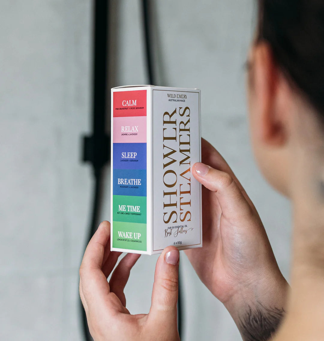 Six Wild Emery shower steamers in a box, featuring natural ingredients and aromatic scents for a relaxing shower experience.