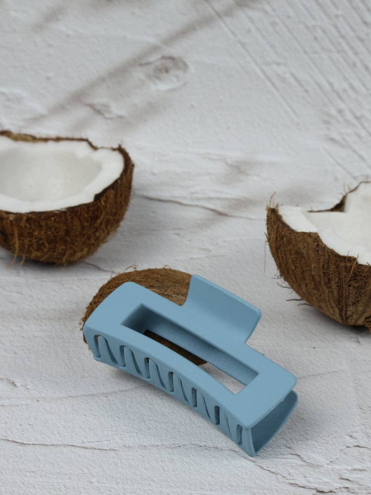Medium cerulean claw clip with elongated rectangular shape from Nakoa The Label, shown holding hair in a natural style.