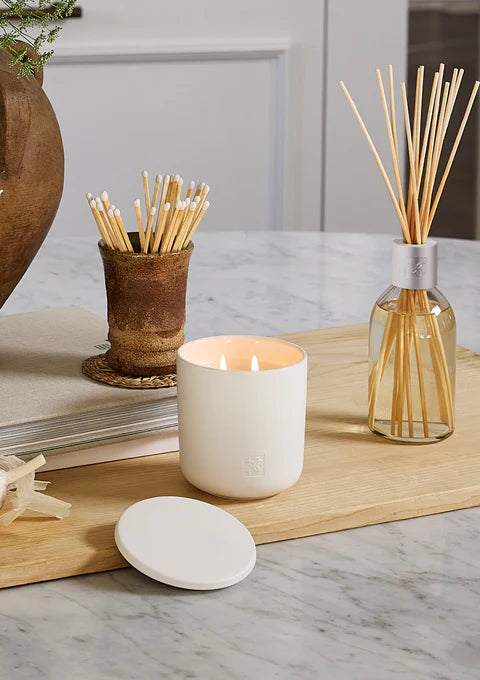 Soy candle from Circa with a white jar, labeled LYCHEE & ROSE, emitting soft light and showcasing a floral and fruity scent.