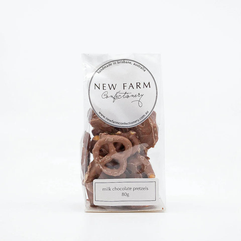 Milk chocolate coated pretzels in a 80g pack by New Farm, showing glossy chocolate-covered pretzels on a white background.