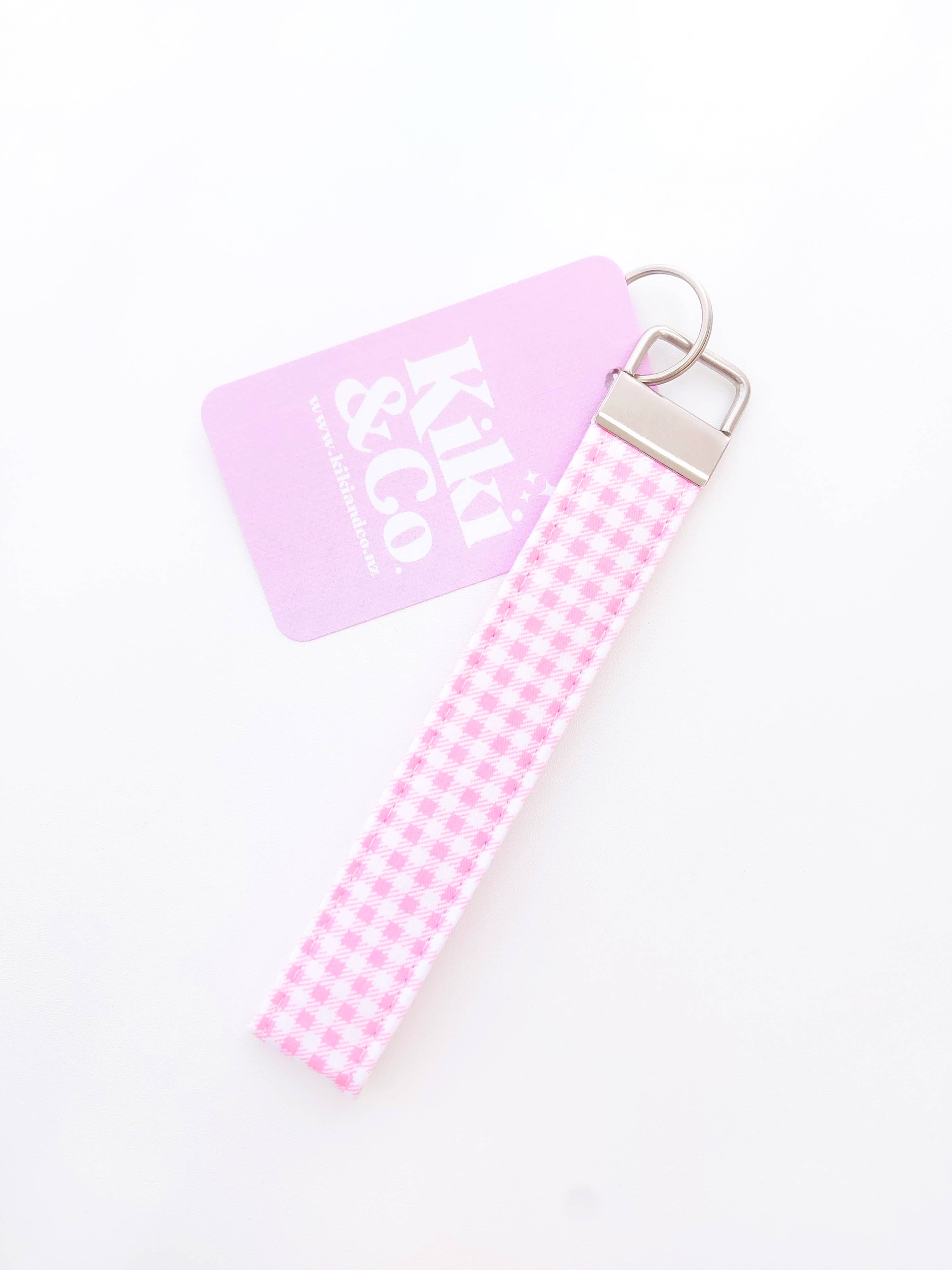 Pink gingham fabric keychain from Kiki & Co. with a small bow detail, attached to a silver keyring.